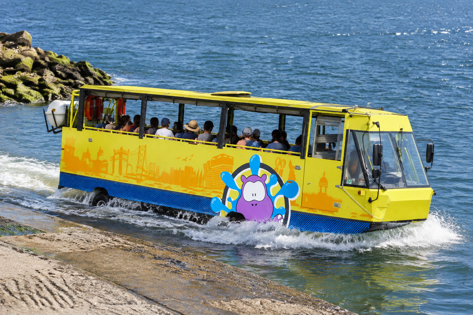 Un autobus amphibie jaune transportant des passagers avance dans l’eau près d’une rampe en pierre.